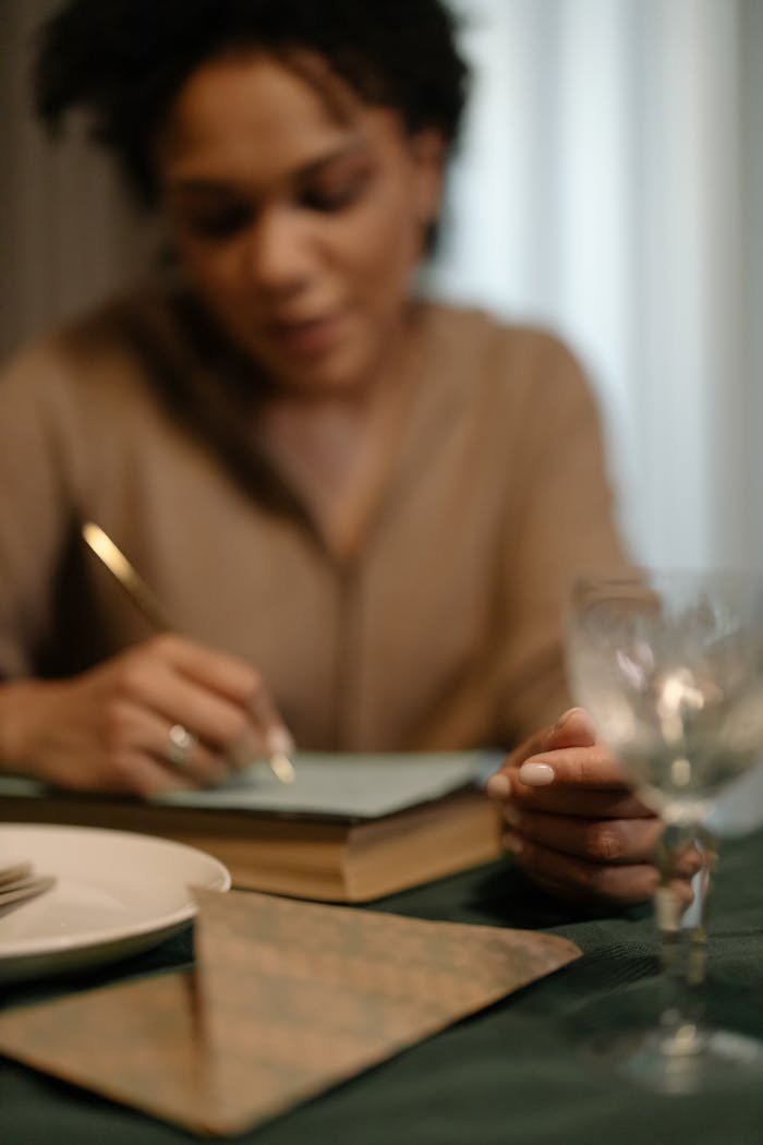 Woman writing in a journal while seated indoors, thoughtful and focused.