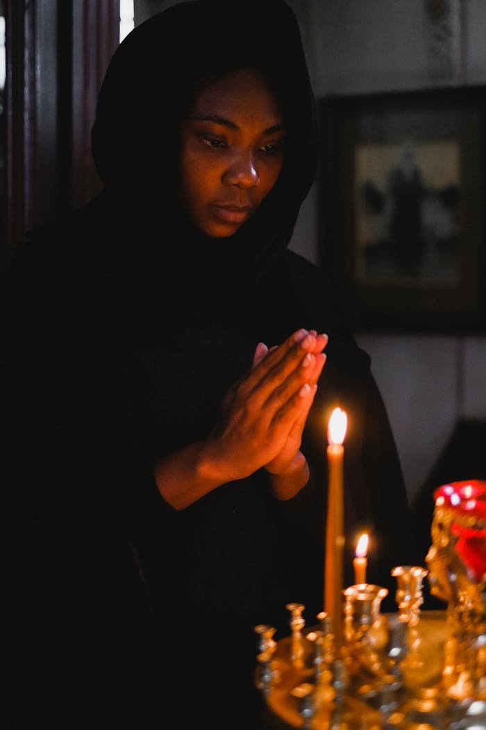 Woman praying in a dimly lit church, surrounded by candles, evoking a sense of peace and spirituality.